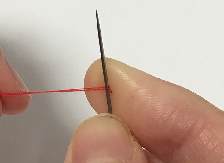 玉結びで糸の先端に針を当てる。