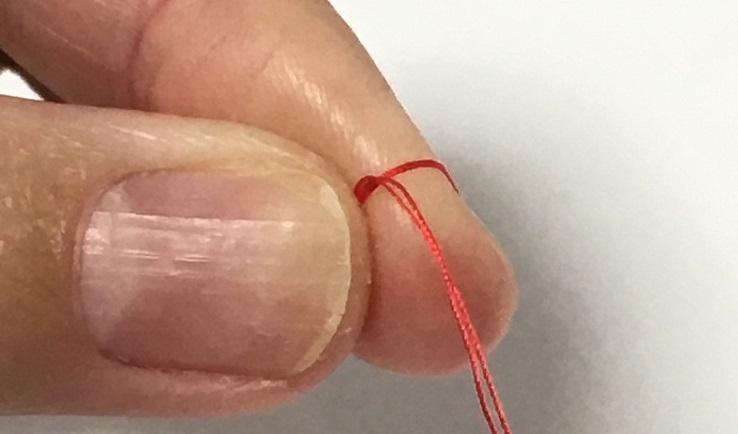 玉結びで人差し指に糸の先端を一周巻き付ける。