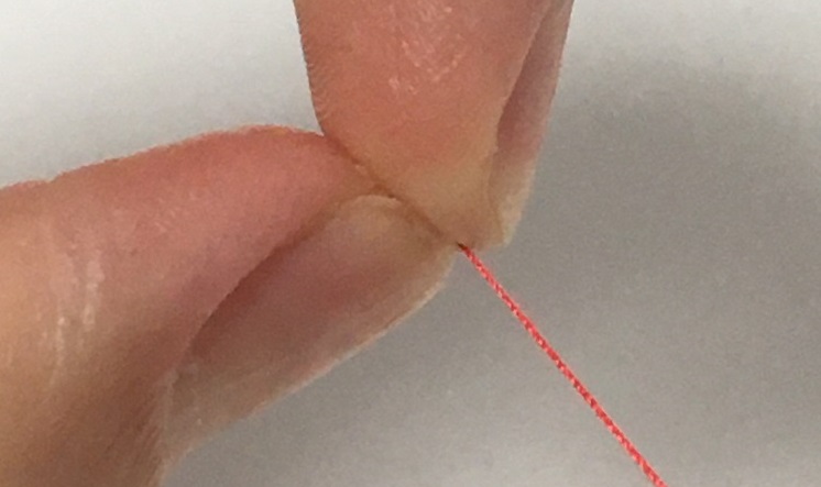 親指と中指の腹で糸を押さえながら糸をスライドさせる。